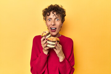 Eager woman reaching for muffins on a vibrant yellow studio background - Powered by Adobe