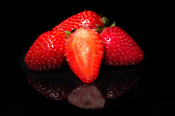 Ripe red strawberry on a black background with reflection