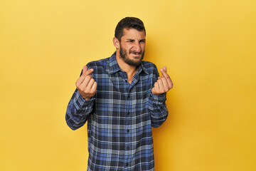 Young Hispanic man on yellow background showing that she has no money.