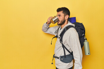Young Hispanic man with camping mug and pack