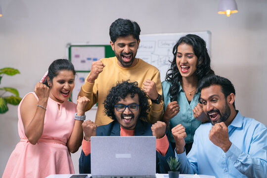 Group of team members celebrating success after seeing received mail from the laptop at office - concept of project deal, new business or client agreement and startup collaboration