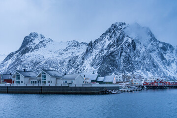 Winter scenic view of a Lofoten village with white and red typical houses and snowcapped mountains...