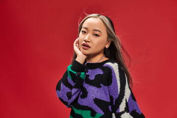 beautiful young asian woman with dyed hair in sweater with animal print posing with hand near face