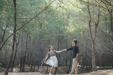 pre wedding photo, couple dancing among the trees in the forest park