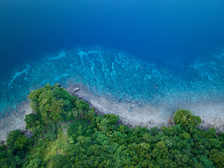 A healthy coral reef fringes a jungle-covered island near Ambon, Indonesia. This remote, tropical region supports some of the greatest marine biodiversity on Earth.