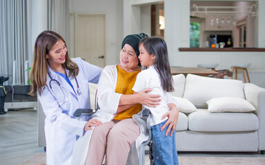 Beautiful Asian female doctor and granddaughter giving encouragement and hugging grandmother who...