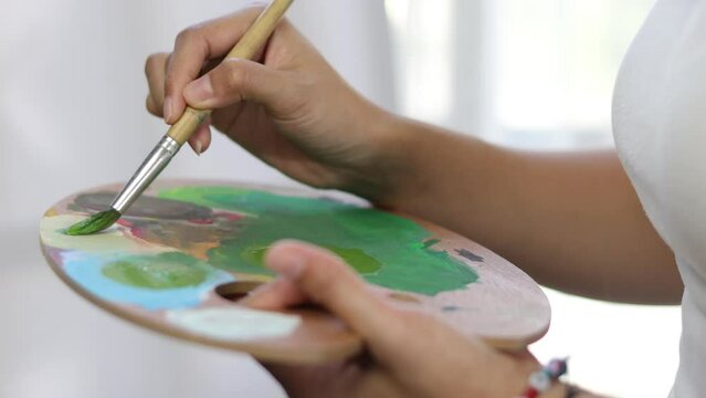 Female artist is drawing and painting her artwork. Young Asian woman drawing in her free time at home.