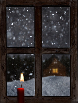 Blick durch ein altes Holzfenster mit Kerze im Winter