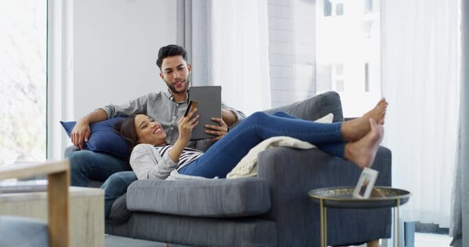 Couple, tablet and credit card for online shopping with talking, conversation and happiness with lying on sofa. Man, woman and internet payment with technology, relaxing and smile on couch of lounge