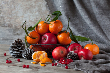 Red apples, tangerines, berries and pine cones on a wooden table. Beautiful Christmas still life, postcard