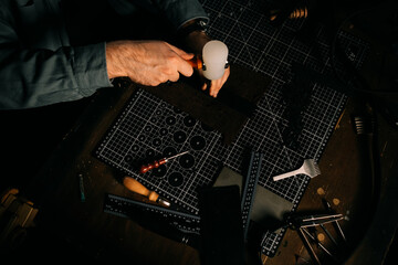 Man Tanner works with leather.hands in workshop with hammer and craft manufacturing of unique...