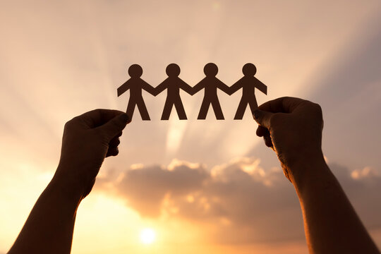 Teamwork and relations concept. woman holding human paper chains at sunrise. People are connected. Concept of human role.  teamwork, family home,society, social network,	
