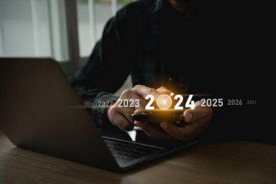 Trends 2024 year concept. Man using mobile laptop and showing virtual sequence count down years 2024 wording for marketing monitor and business planning in new year. Technology new year concept.