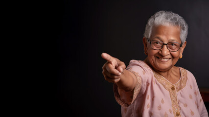 Happy senior indian woman point her finger at copy space for promotion
