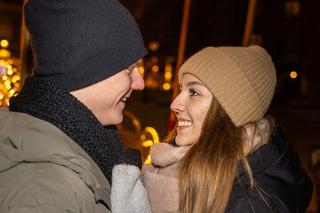 Positive, cheerful couple hugging during x-mas evening. Decorated lights on the streets outdoors