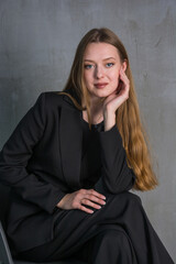 Young beautiful woman, fashion model, in a black suit in the studio