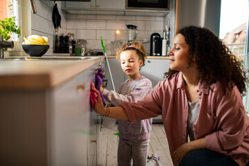 Mother and daughter cleaning home kitchen