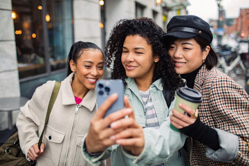 Beautiful young multiethnic women taking selfie in the city