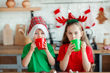 Brother and sister, little boy and girl eating Christmas cookies and drinking drink in Christmas...