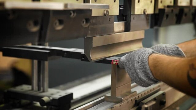 The engineer does the bending of the metal sheet on a hydraulic machine