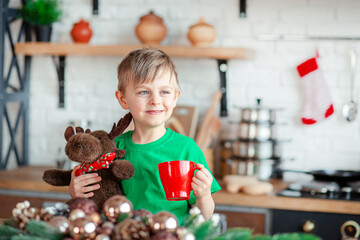 Cute little boy eating Christmas cookies and drinking a drink in Christmas decorations in the...