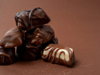 A varied assortment of chocolates arranged on a rich brown background. Chocolate candies close-up.