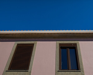Detalhe da fachada de um prédio com 2 janelas.