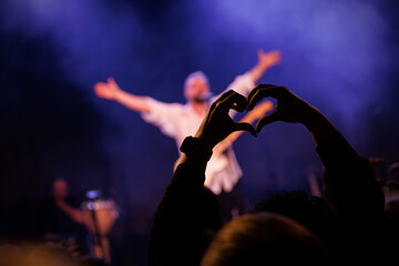 The concert music fan make a heart shape with their hands. - obrazy, fototapety, plakaty
