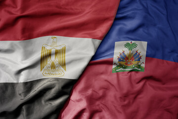 big waving national colorful flag of haiti and national flag of egypt .