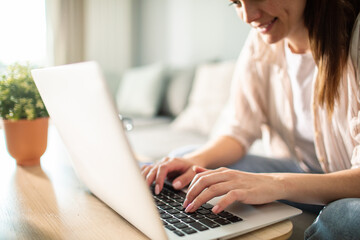 Young woman sitting on couch typing on laptop at home