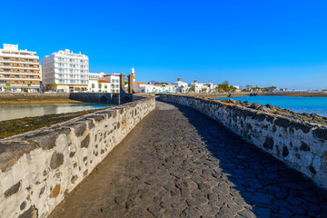 City and beach skyline from the narrow stone walkway to the Castillo de San Gabriel Castle 16th century fortress, in Arrecife, Spain, on the Canary island of Lanzarote.