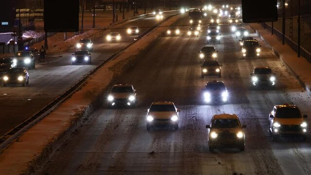 cars drive on winter highway at night. car traffic transport on multiple lanes snowed expressway
