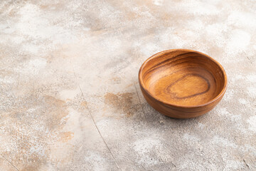 Empty brown wooden bowl on brown concrete. Side view, copy space