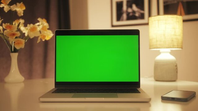Close up table of distant worker at home. Laptop with chroma key green screen. Remote work, distance learning, technology concept.