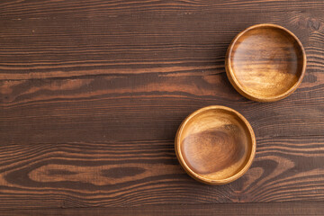 Two empty brown wooden bowl on brown wooden. Top view, copy space