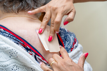 Doctor or nurse applying medical patch to senior woman at hospital. High quality photo