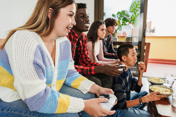 Multiracial young friends having fun playing video games at home - Gaming, holidays and...