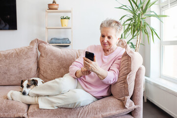Relaxed mature old 60s woman with phone at home