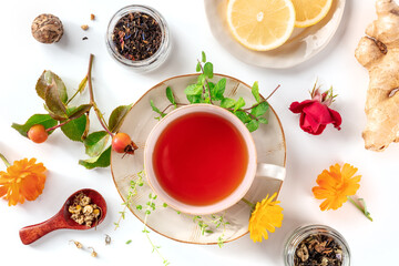 Tea with various ingredients. Teacup and herbs, fruits, and flowers, overhead flat lay shot on a...