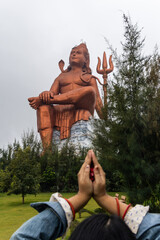 hindu god lord shiva isolated statue with blurred praying hand at morning from unique perspective