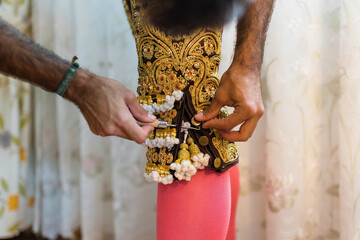 Detail of trainer helping matador to put on pants