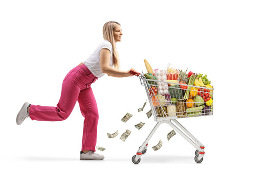 Full length profile shot of a young female running with food in a shopping cart and money falling from the cart