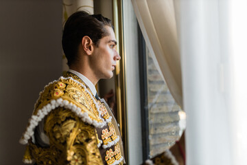 Hispanic male bullfighter looking out window