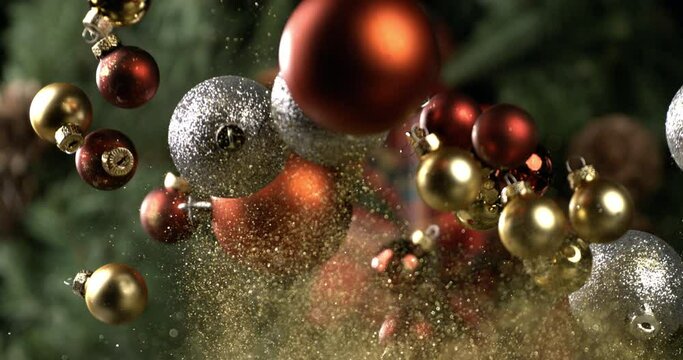 Extreme slow motion macro of christmas tree decoration balls flying with golden sparkling glitter dust particles splashing explosion isolated on festive holidays background at 1000 fps.