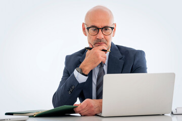 Mid aged businessman sitting at desk and using notebook for work against isolated background - 691609046