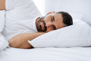 Middle aged bearded man struggles with insomnia lying in bedroom