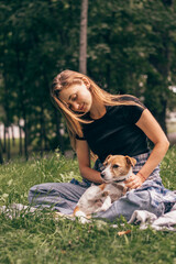 A young positive woman hugging friendly Jack Russell Terrier dog, enjoying happy moments together while walking in the park on a summer day.