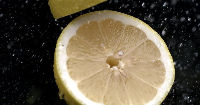 Super slow motion macro of fresh juicy bio organic yellow citrus lemon fruit is being cut in middle with sharp blade kitchen knife at 1000 fps isolated on soft background