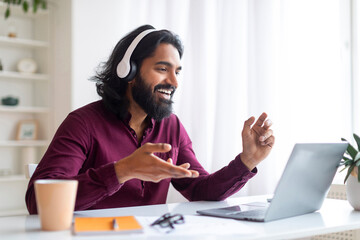 Portrait Of Smiling Indian Man In Headset Making Video Call With Laptop