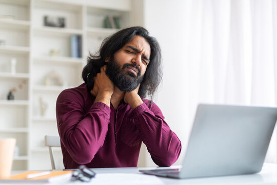 Indian Freelancer Man Feeling Neck Pain While Working With Laptop At Home